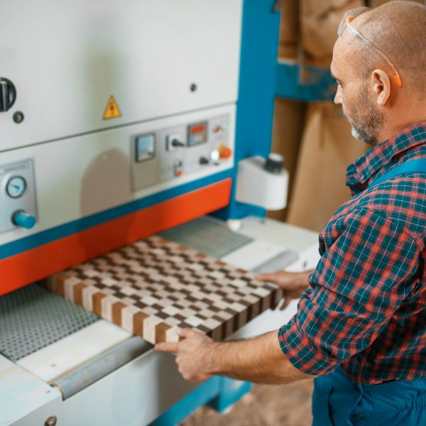 Carpenter works on woodworking machine, factory